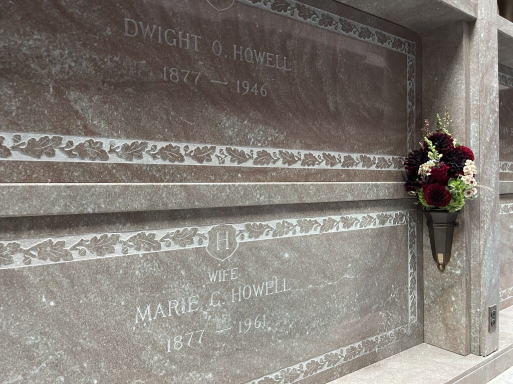 An angled view of the Howells' marble tombs/niches and the bouquet of red dahlias in the affixed vase. 