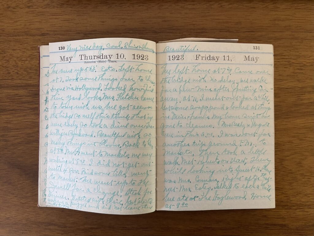 The diary lies open on a wood desk. It's open to the pages documenting Thursday, May 10, 1923, and Friday, May 11, 1923. Both pages are completely filled with cursive in ink faded to green. 