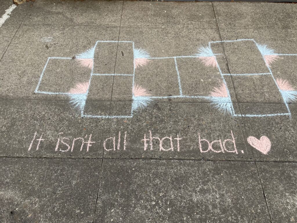 A hopscotch and the sentence "It isn't all that bad." with a heart at the end, written in chalk on a neighborhood sidewalk. Spotted during one of my end-of-summer evening walks. 