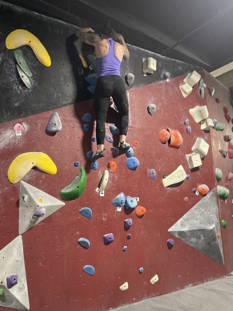 Kelsey climbing up an easy route on an indoor bouldering wall. 