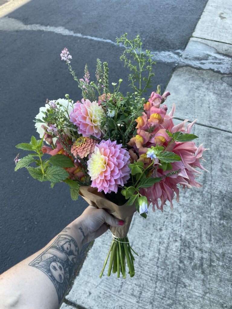 A fresh, beautiful, end-of summer bouquet of pink, orange, and white dahlias and snapdragons and lots of green filler plants. 